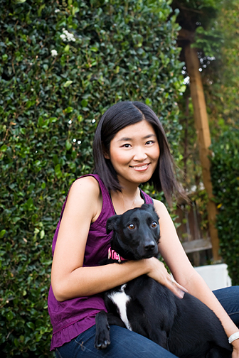 Photo of creative animal photographer Grace Chon holding a black dog sitting across her lap.