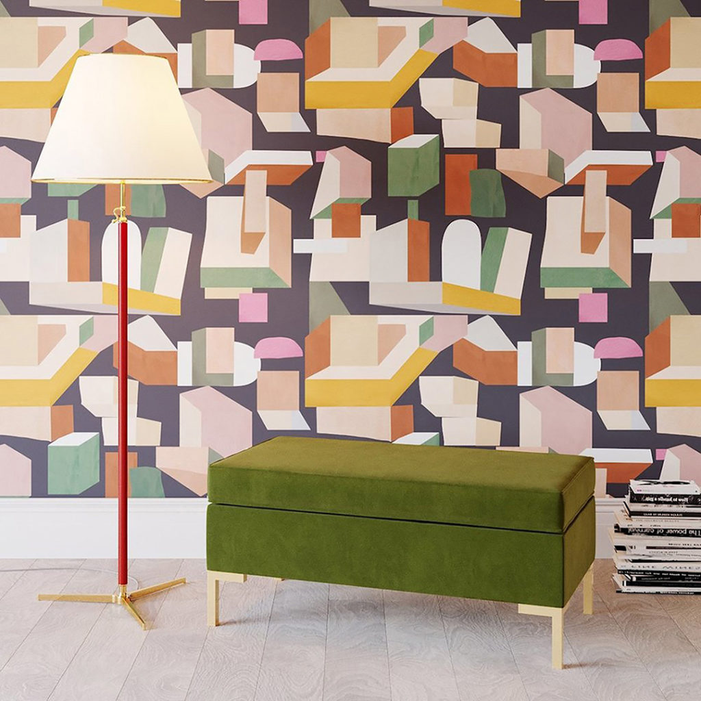 Handpainted, geometric wallpaper in muted colors brings together an eclectic interior design with contemporary furniture by a stack of books.