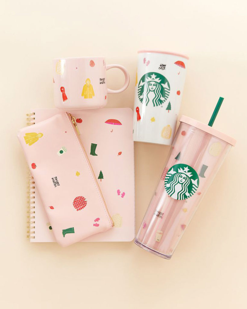 Still image of pink and green Starbucks cups, mugs and stationery items flat lay on a pink salmon colored backdrop.