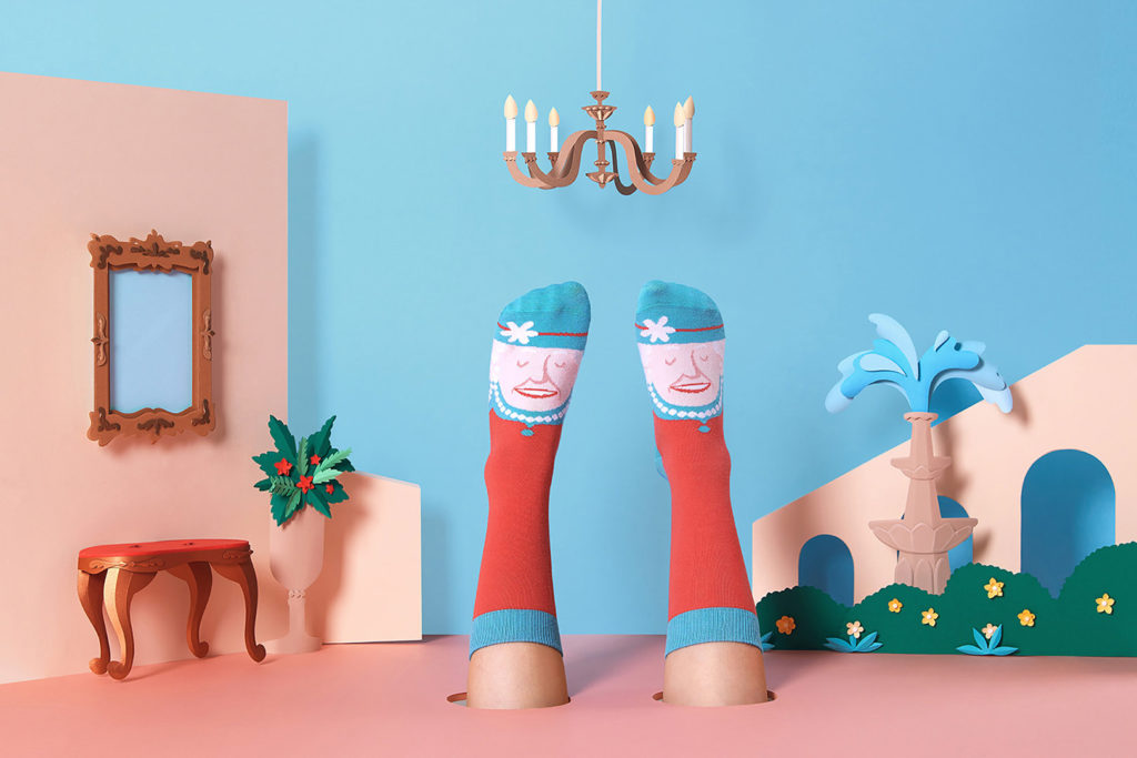 Whimsical photoshoot of playful socks surrounded by Yeni Kim's paper art illustrations as fountains, mirrors and more.
